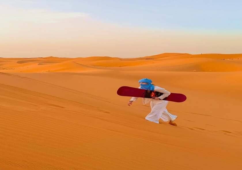 Sandboarding on the golden dunes of the Sahara Desert in Morocco