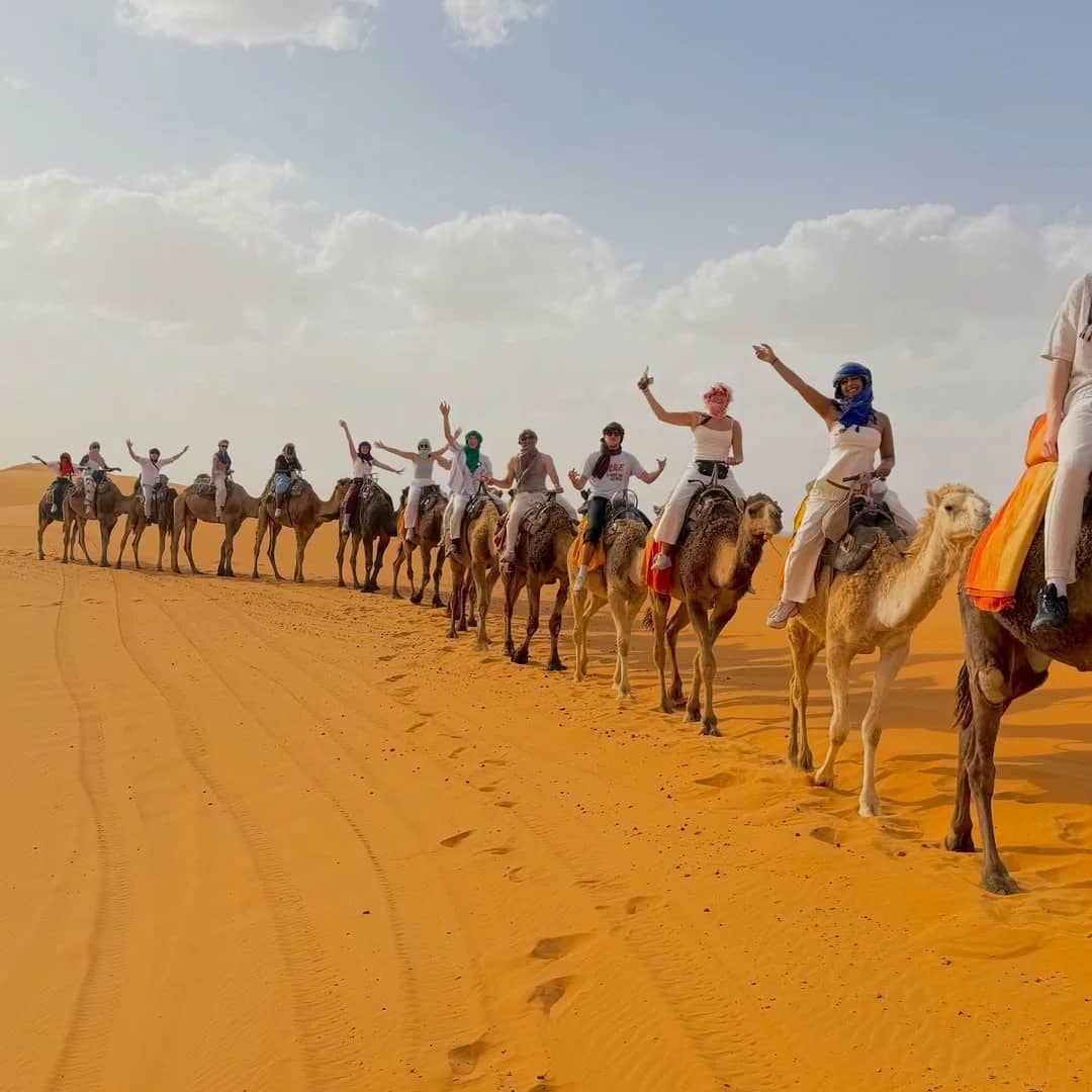 Travelers enjoying a camel trek across the Erg Chebbi dunes during a 10 Day Morocco Tour from Agadir